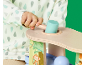 Peuter speelt met houten speelgoed met hamer en ballen, gekleed in een romper met regendruppelpatroon.
