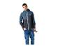 Man in blauw-grijs outdoorjack en jeans, met wandelstokken in de hand.