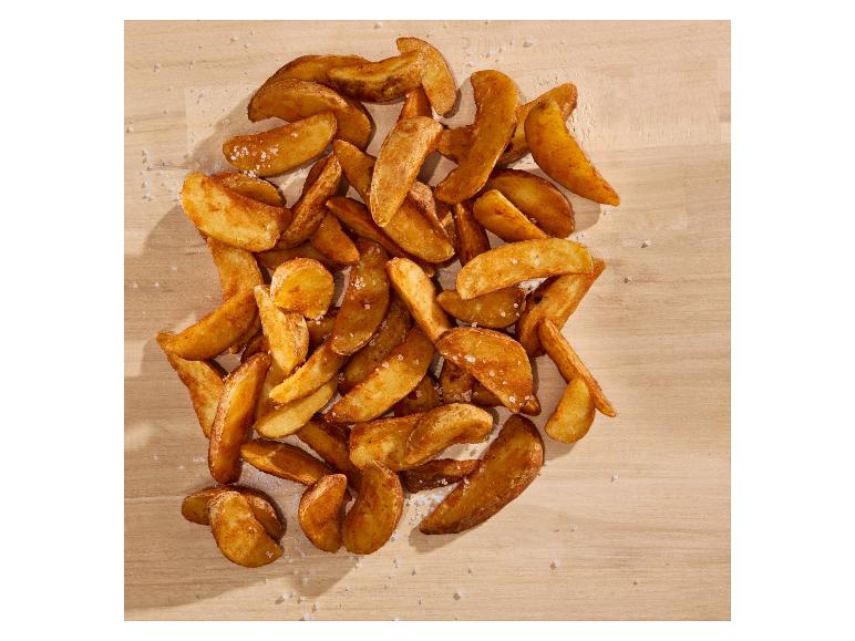 Goudbruine, knapperige aardappelpartjes bestrooid met zeezout op een houten achtergrond.