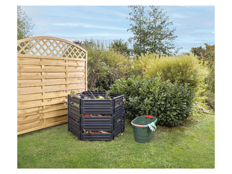 Tuincompostering: composter, emmer en houten schutting.