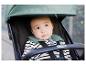 Baby in een kinderwagen, met gestreept shirt en groene kraag.