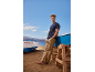 Man in blauw T-shirt en beige broek op strand met boten, nummer 7GC305.95