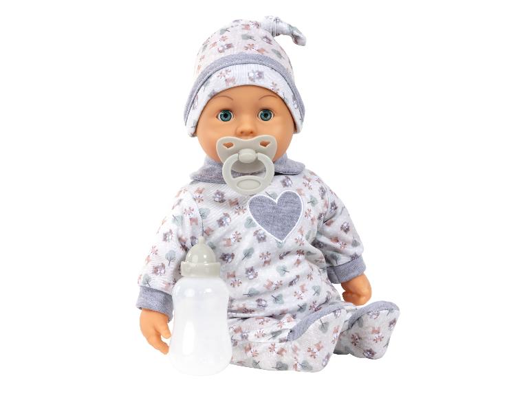 Babypop in een bedrukt rompertje en muts met speen en fles.