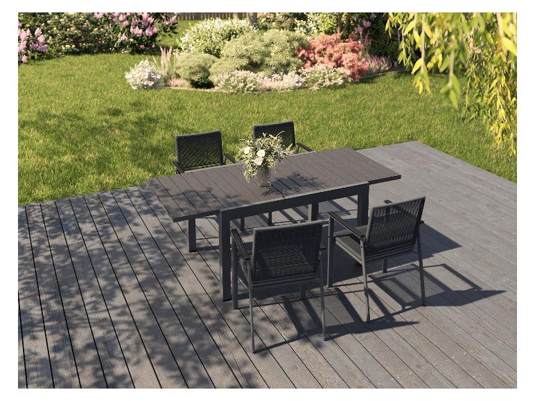 Buiten eethoek met een tafel en zes stoelen op een terras met uitzicht op een tuin.