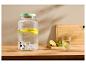 Glazen drankdispenser met citroen en munt, naast een glas water.