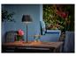 Tafellamp op een houten tafel met bloemen en een drankje op een terras.