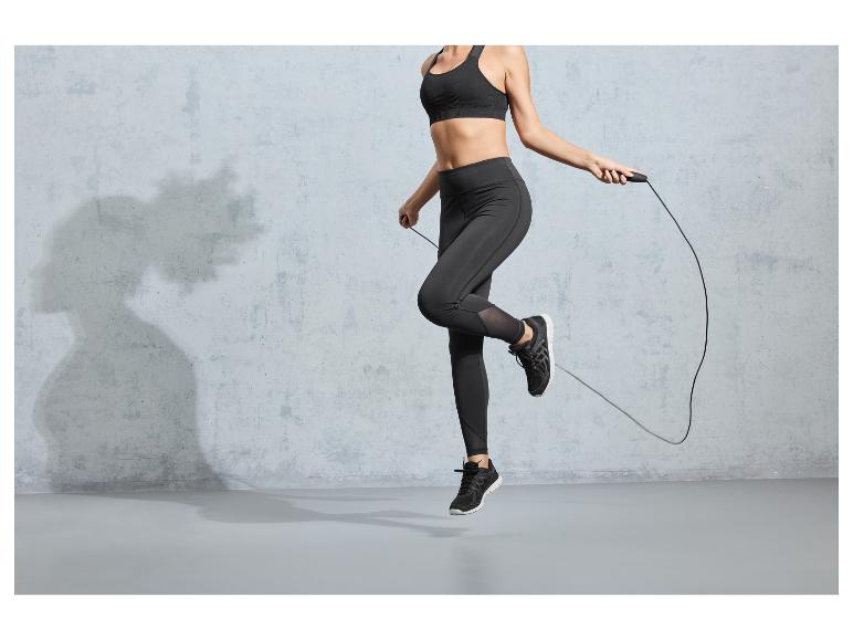 Een vrouw in sportkleding springt over een springtouw.