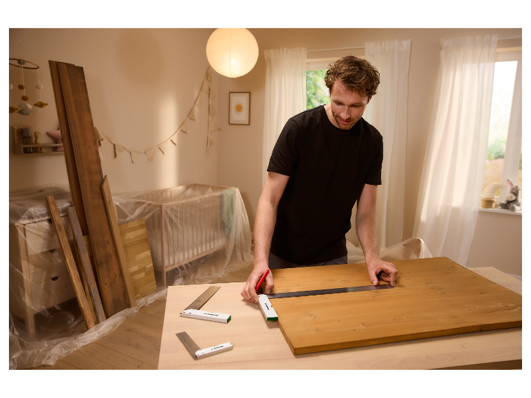 Een man gebruikt Parkside winkelhaken en een meetlat om een houten plank te meten.