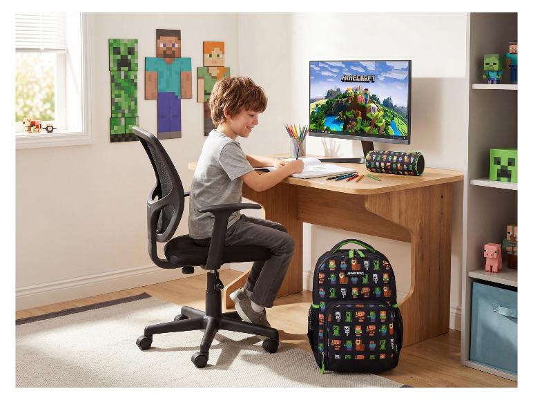 Jongen tekent aan houten bureau met rugzak en videogame-thema decoratie.