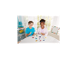 Twee kinderen spelen met strijkkralen en maken kleurrijke vormen op een witte tafel.