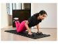 Een vrouw doet push-ups met push-up bars op een zwarte yogamat van Decathlon.