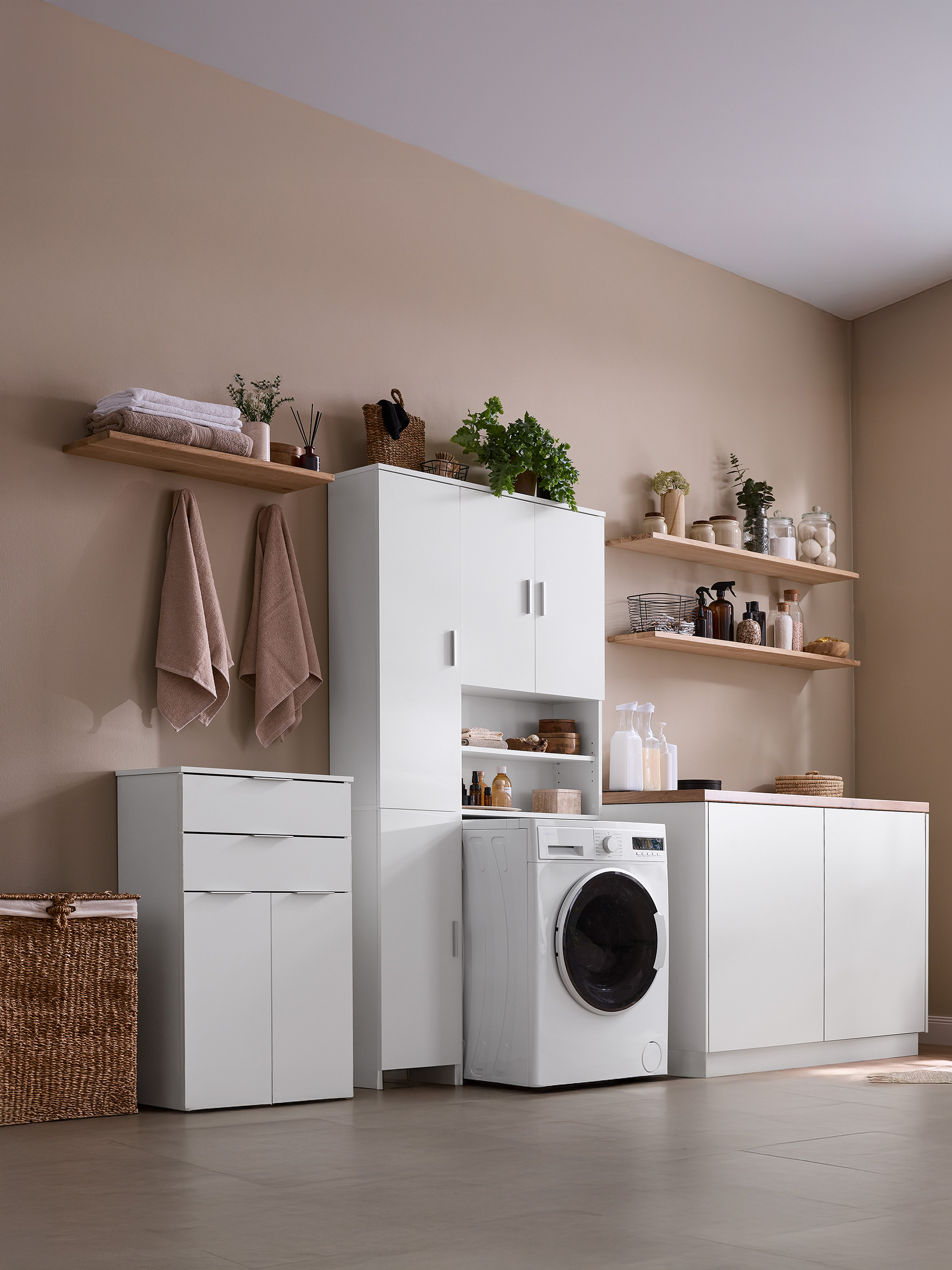 Moderne wasruimte met witte kasten, planken, een wasmachine en een rieten mand.