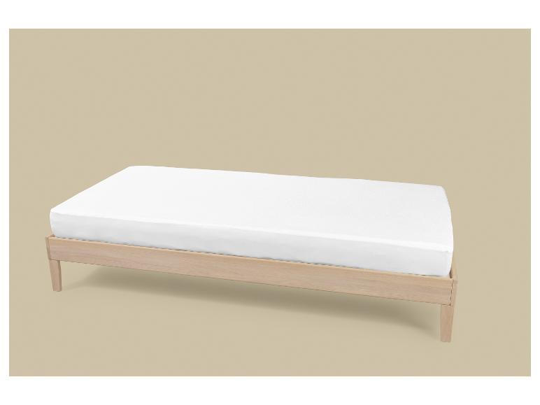 Een licht houten bedframe met een wit matras op een beige achtergrond.