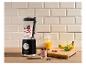 Zwarte blender met bessen en yoghurt, naast fruit en sap op een houten plank.