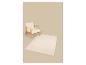 Lichte houten fauteuil met witte kussens en een beige vloerkleed op neutrale achtergrond.