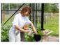 Vrouw giet peterselie water met een gieter in de tuin.