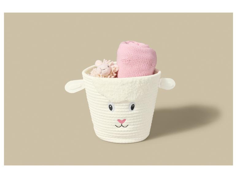 Witte opbergmand in de vorm van een schaap met een roze deken en een schapenknuffel.