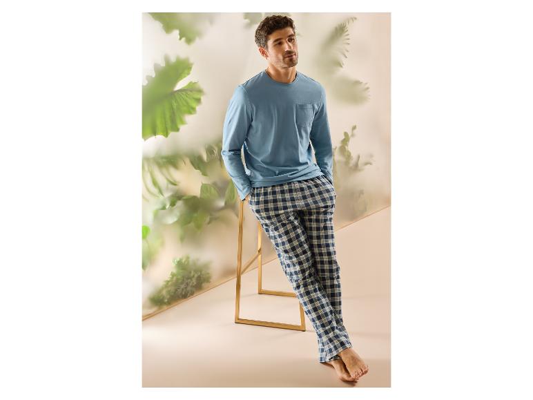 Man in blauwe pyjama met lange mouwen en blauw-wit geruite pyjamabroek, leunend op een kruk.