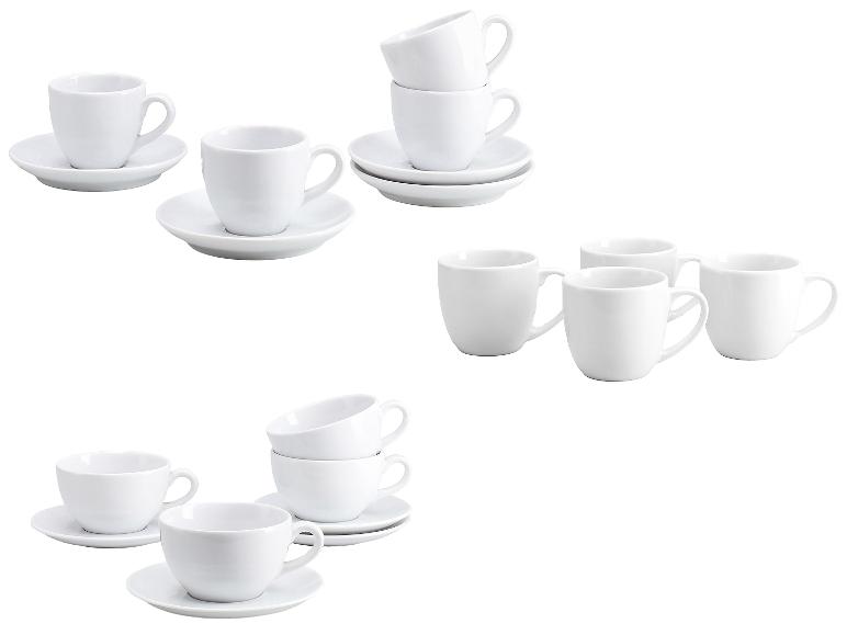 Witte keramische espressokopjes en schoteltjes, sommige gestapeld, andere los.