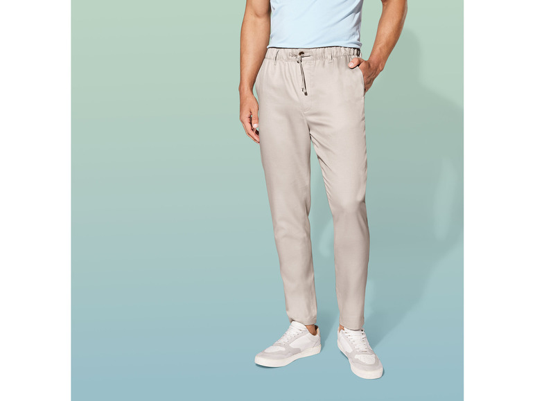 Beige broek met elastische tailleband en witte sneakers.