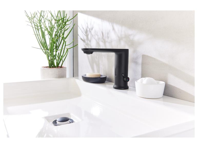 Zwarte kraan, wastafel en moderne badkameraccessoires.