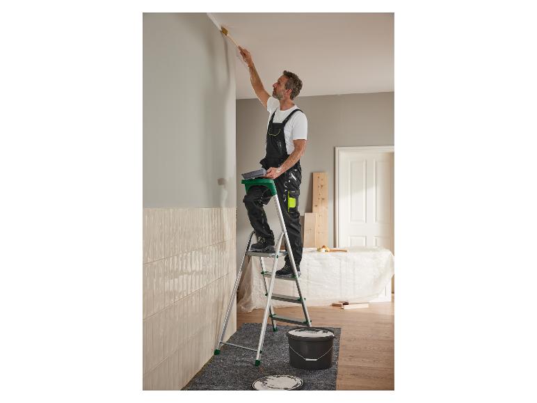 Een man schildert een muur met een ladder en een kwast.