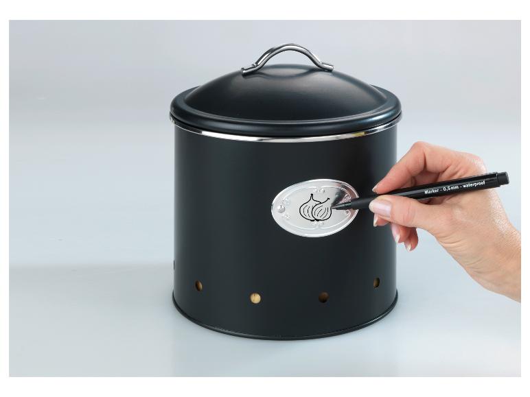 Zwarte metalen opbergcontainer met deksel, waarop met een marker wordt geschreven.