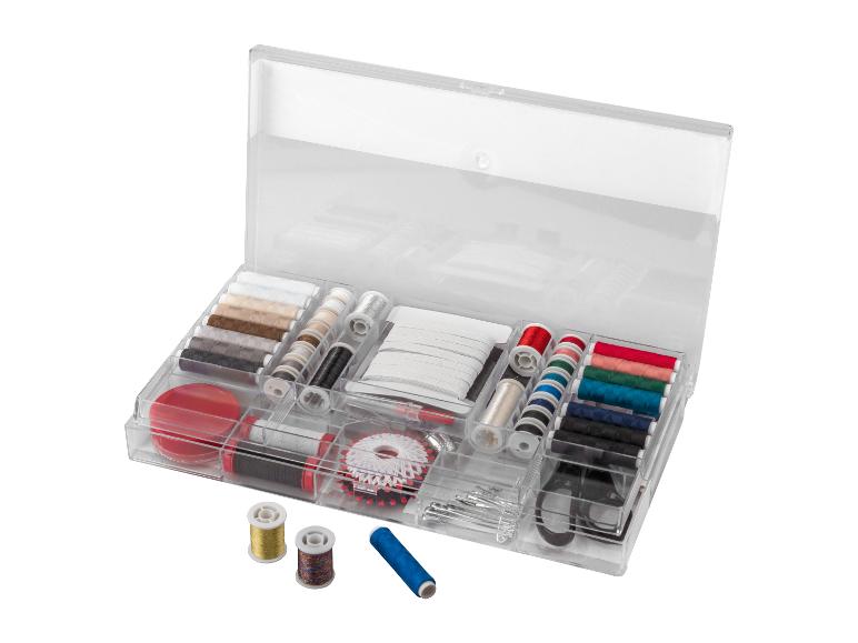 Transparante naaidoos met garenklosjes, knopen en andere naaiaccessoires.