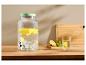 Glazen drankdispenser met citroenen en munt, glas water met citroen op een houten tafel.