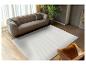 Wit vloerkleed met golfpatroon in een moderne woonkamer met bank en leren fauteuil.