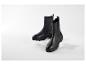Twee zwarte Chelsea boots met grove zolen op witte platforms.