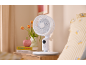 Witte tafelventilator op een houten nachtkastje naast het bed.