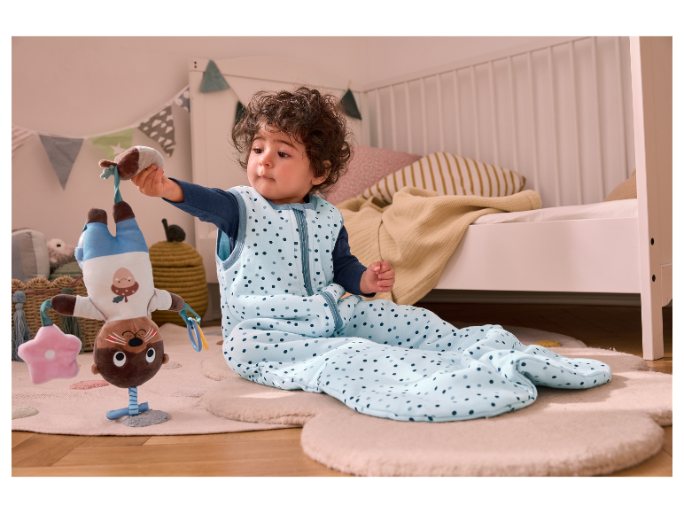 Baby in een slaapzak met een speeltje.