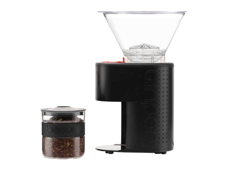 Zwarte koffiemolen en glazen pot met gemalen koffie op een witte achtergrond.