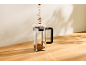 Koffie wordt in een glazen cafetière op een houten tafel gegoten.