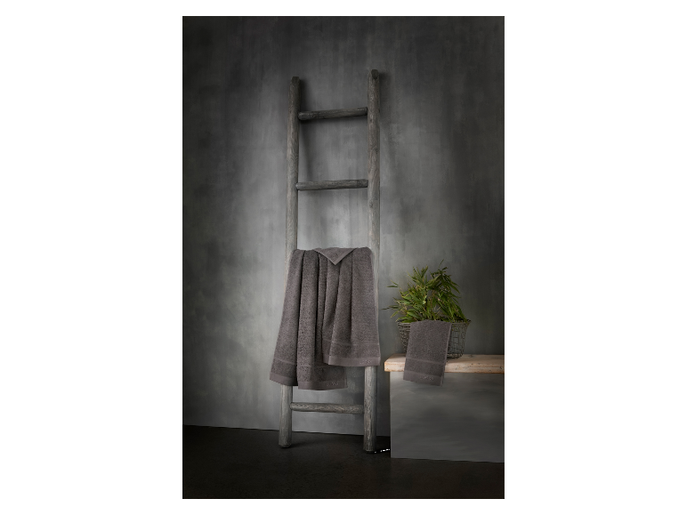 Grijze Loeks handdoeken op een rustieke houten ladder.