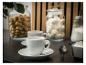 Twee witte espressokopjes met schotels, een lepel en potten met koekjes en meringues.