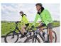 Twee mensen fietsen met felgele jassen.