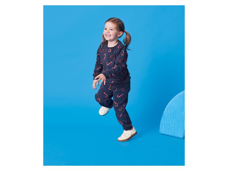 Klein meisje in een donkerblauw trainingspak met zuurstokprint.