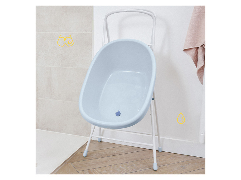 Een babybadje met een wit metalen frame in een badkamer.