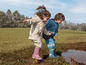 Twee kinderen spelen in de modder met regenlaarzen.