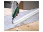 Hand met handschoen gebruikt een slijpmachine om een metalen buis op een gestructureerd oppervlak te bewerken.