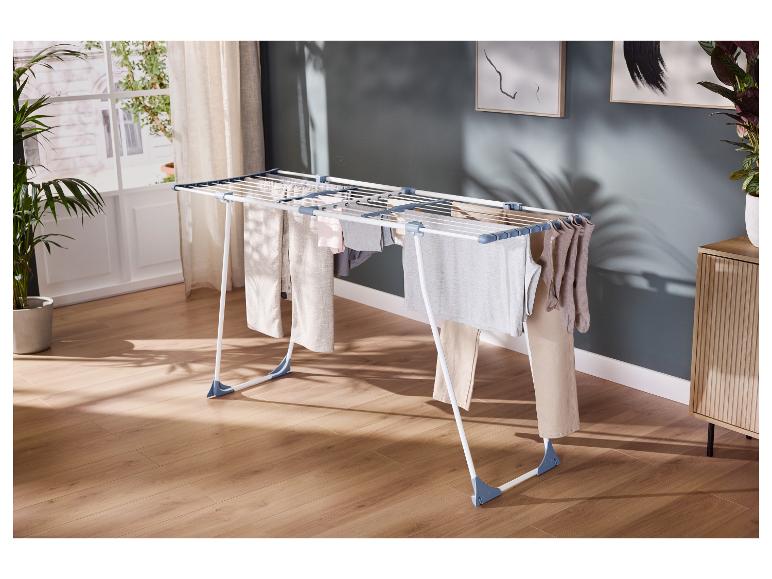 Droogrek met diverse kledingstukken in een lichte kamer met houten vloer.