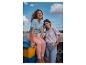 Twee vrouwen in casual tops en jeans bij het water, één in een gestreepte top en roze jeans, de andere in een patroon top en lichtblauwe jeans.