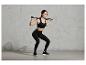 Een vrouw in sportkleding doet squats met een trainingsstang.