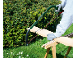Man zaagt een houten plank met een zaag op een houten zaagbok in de tuin.