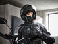 Een motorrijder met helm, handschoenen en een nekwarmer.