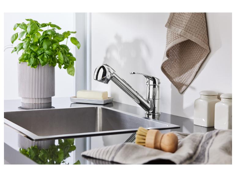 Chromen keukenkraan, roestvrijstalen spoelbak en keukengerei.