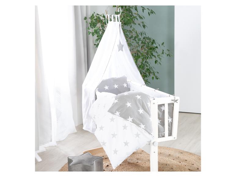 Babybedje met hemel en beddengoed met sterrenpatroon in een kinderkamer.