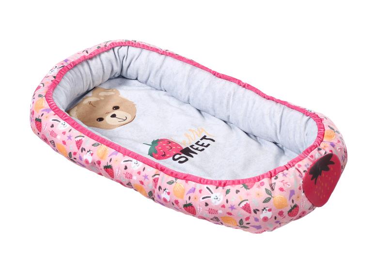 Roze babynestje met aardbei-, citroen- en konijnenpatronen, met een beer aan de binnenkant.